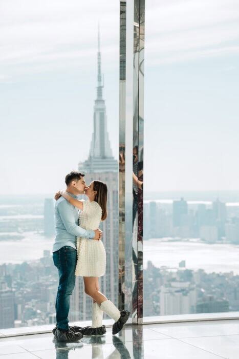 Romantic couple embracing with New York City skyline and Empire State Building in the background.